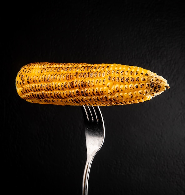 close-up-view-corn-cob-with-fork-black-wall_141793-10711.jpg